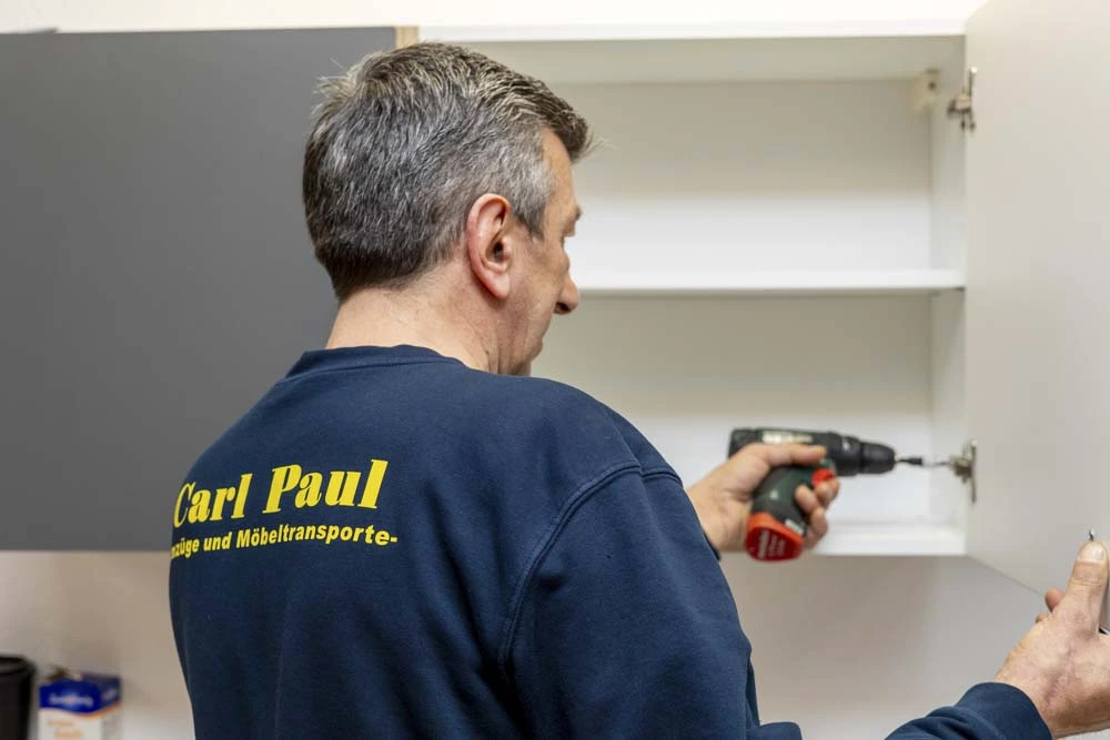 Mitarbeiter von Carl Paul montiert eine Schranktür mit einem Akkuschrauber